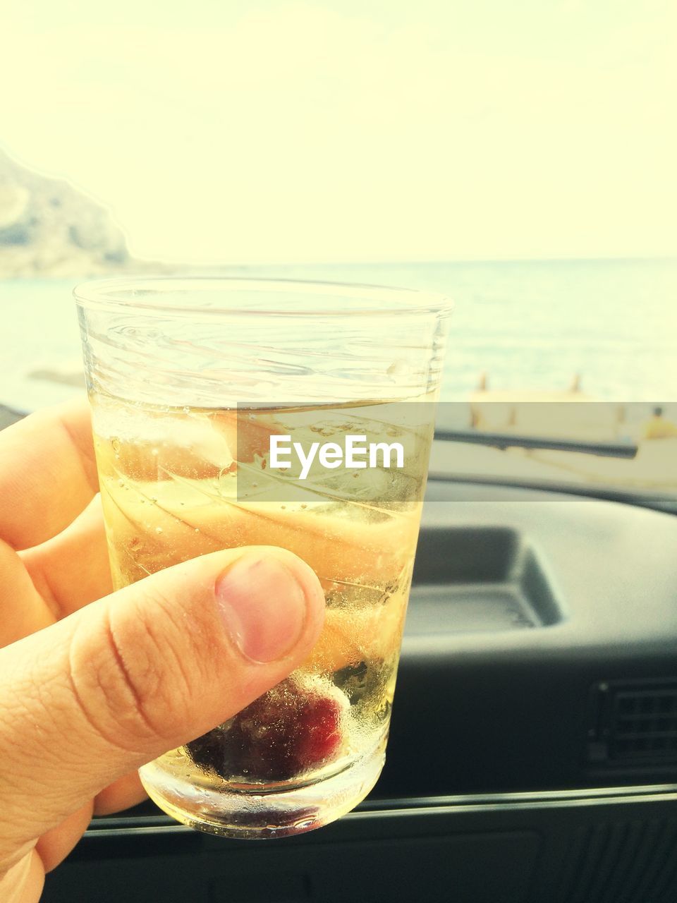 Cropped image of hand holding drinking glass with wine in car