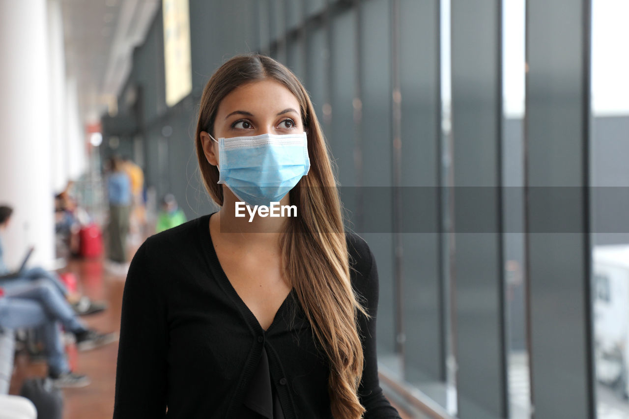 Woman wearing mask looking away in airport