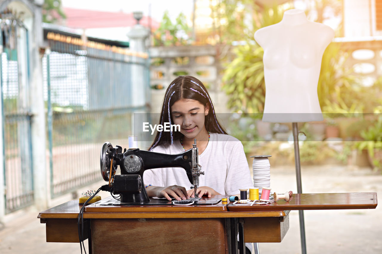 Girl stitching with sewing machine in workshop