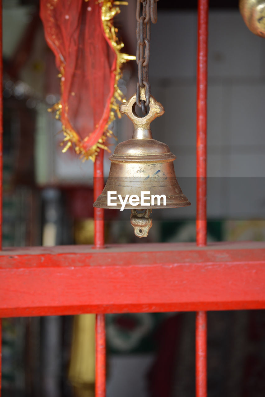 CLOSE-UP OF RED BELL HANGING OUTSIDE TEMPLE