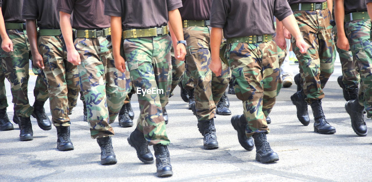 group of people, government, armed forces, military, parade, crowd, uniform, clothing, military uniform, low section, soldier, marching, large group of people, in a row, person, army, military parade, day, camouflage clothing, human leg, event, footwear, street, city, shoe, security, weapon, men, outdoors