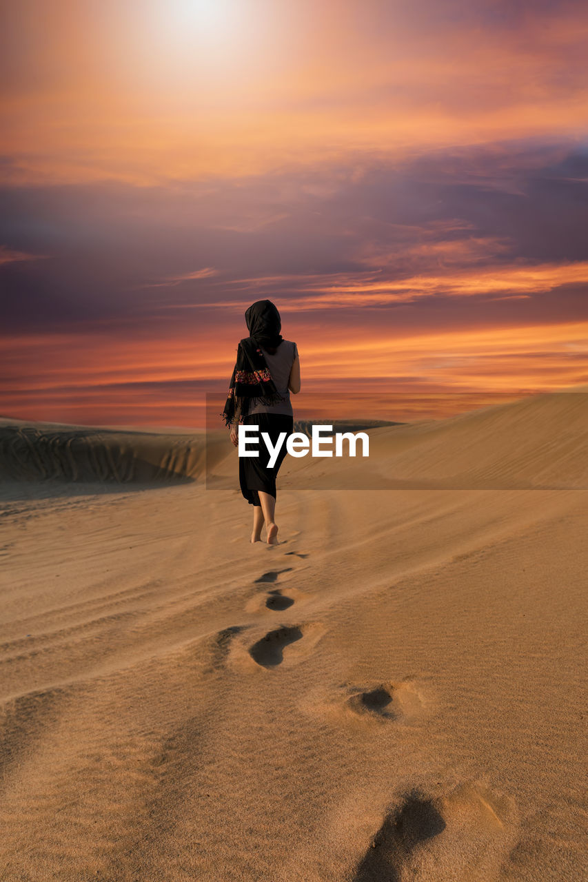 Rear view of woman in desert during sunset