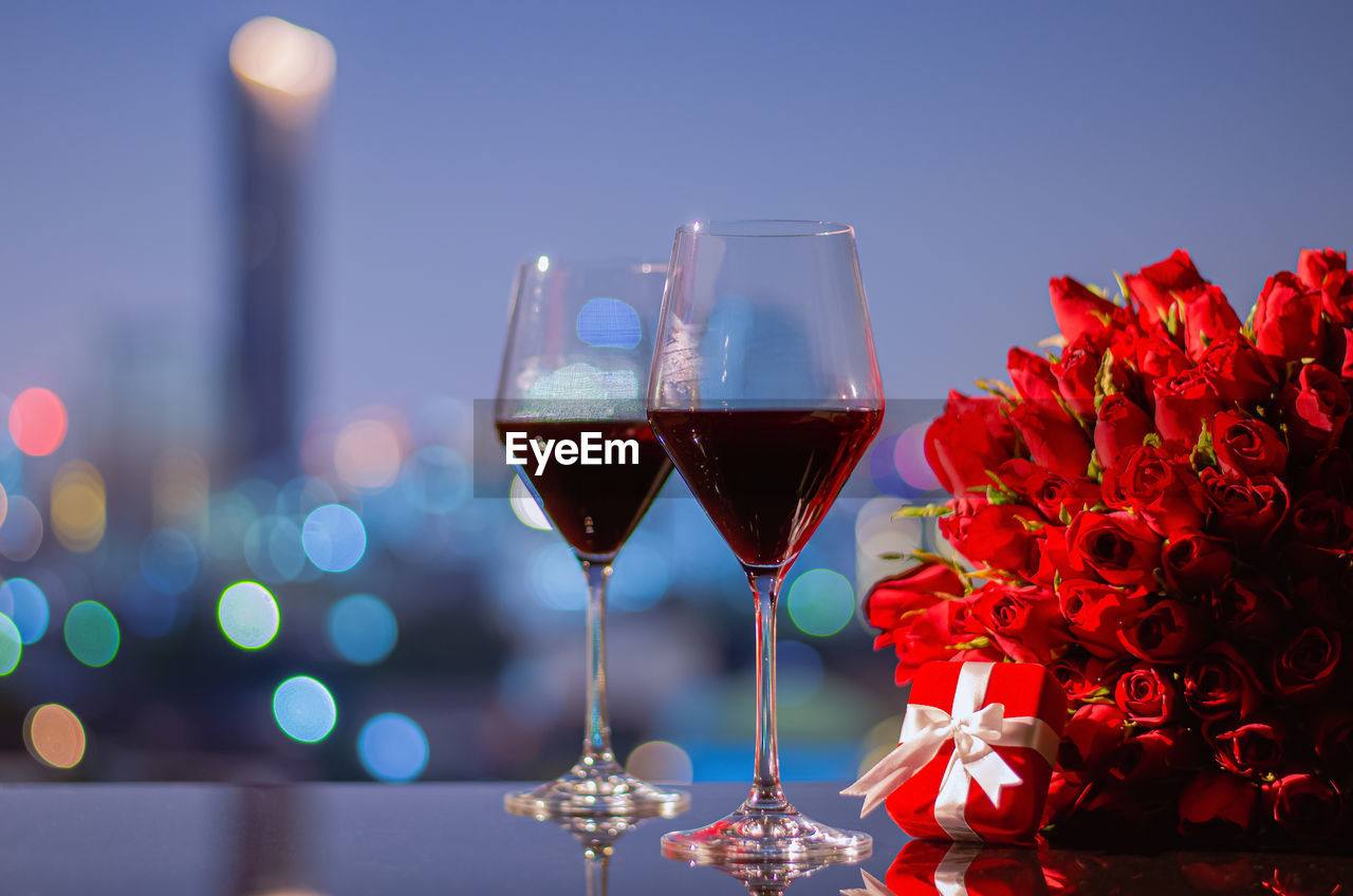 CLOSE-UP OF RED WINE ON GLASS TABLE AGAINST ILLUMINATED LAMP