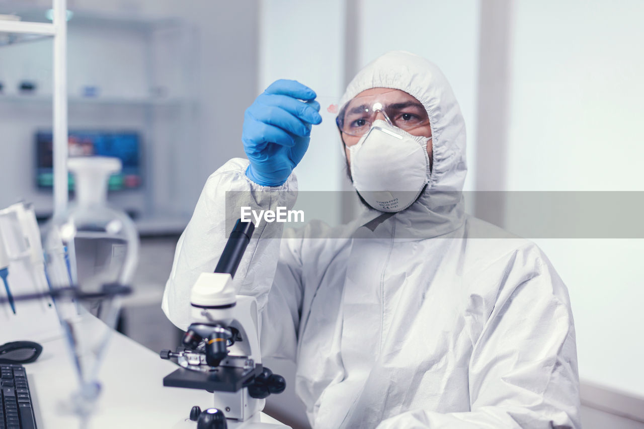 portrait of scientist holding dentures while standing in laboratory