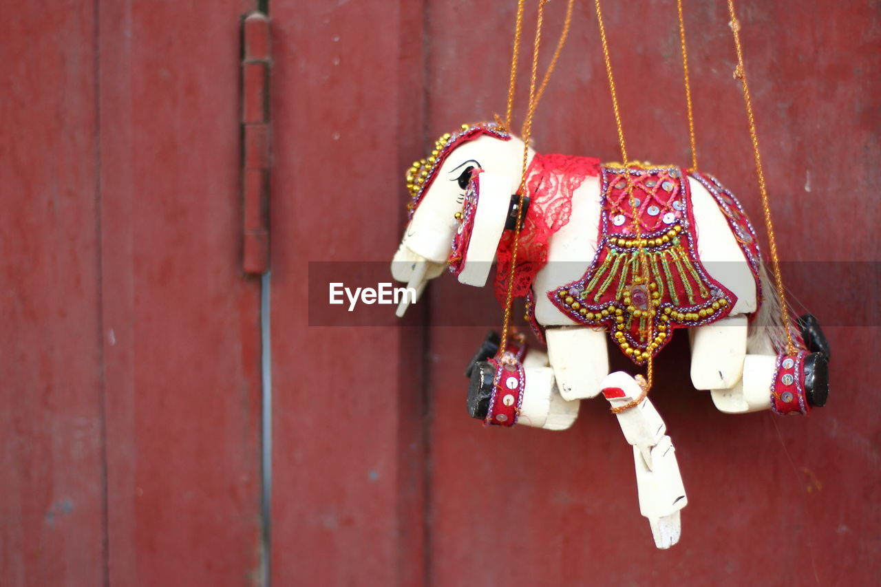 Close-up of puppet hanging against wooden wall