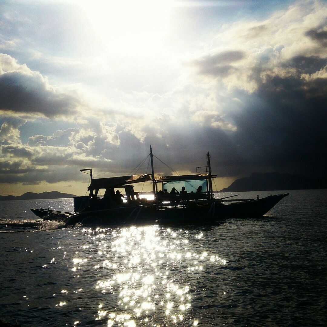 Passenger boat sailing in sea against cloudy sky