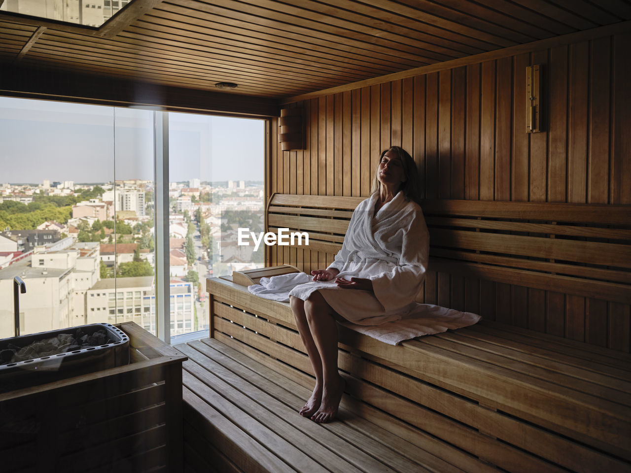 Relaxing senior woman sitting on wooden sauna at health spa