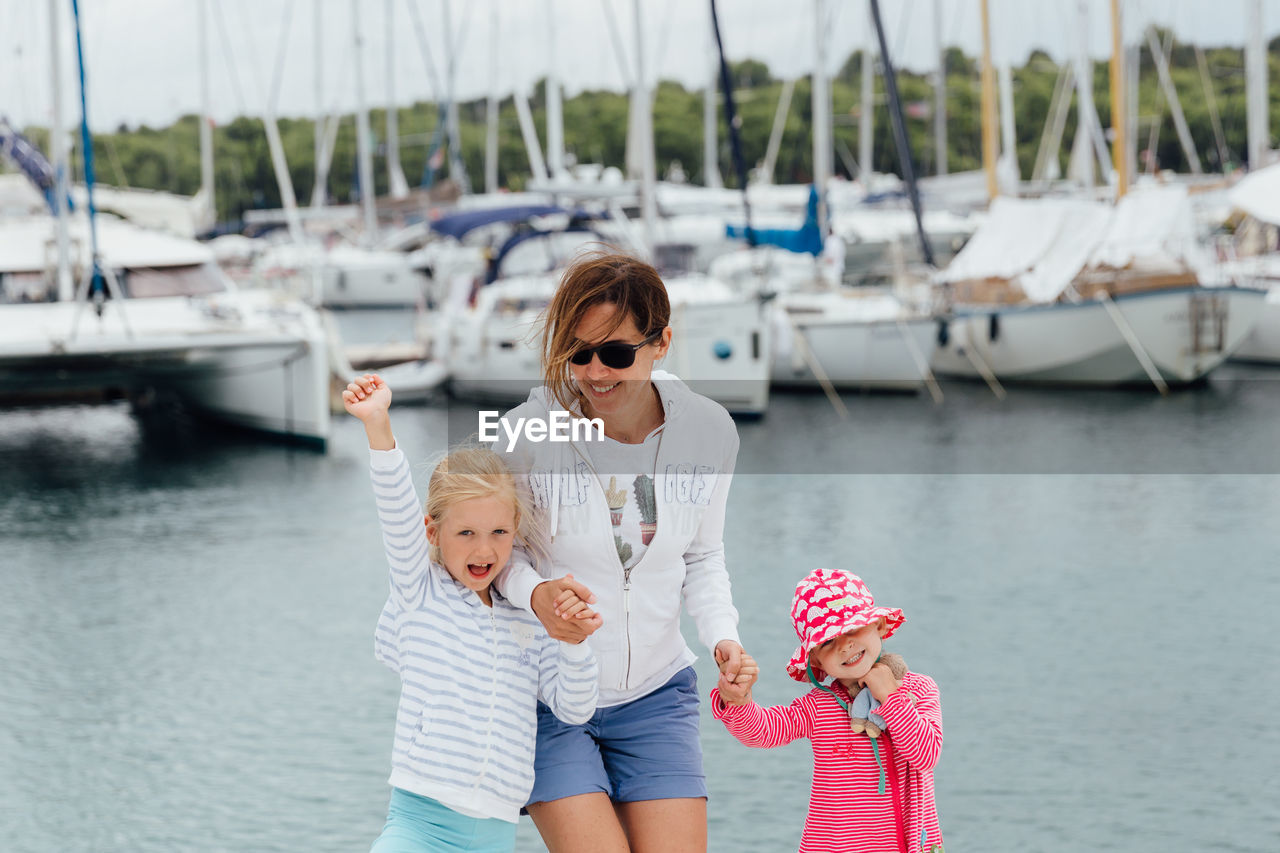 Mother with cute daughters standing at harbor