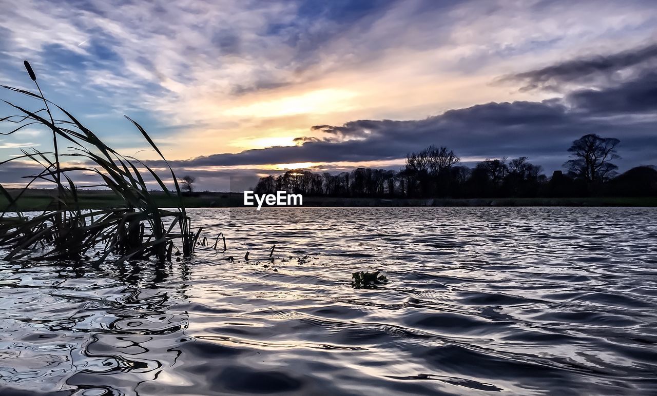 Scenic view of lake against sunset sky