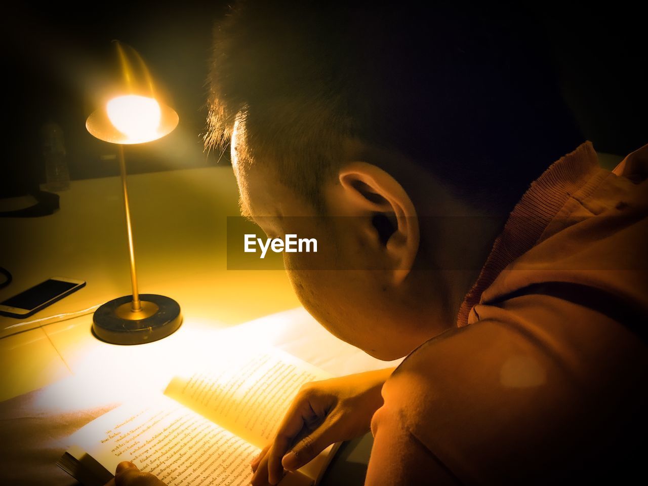 CLOSE-UP PORTRAIT OF BOY HOLDING BOOK IN ILLUMINATED LAMP