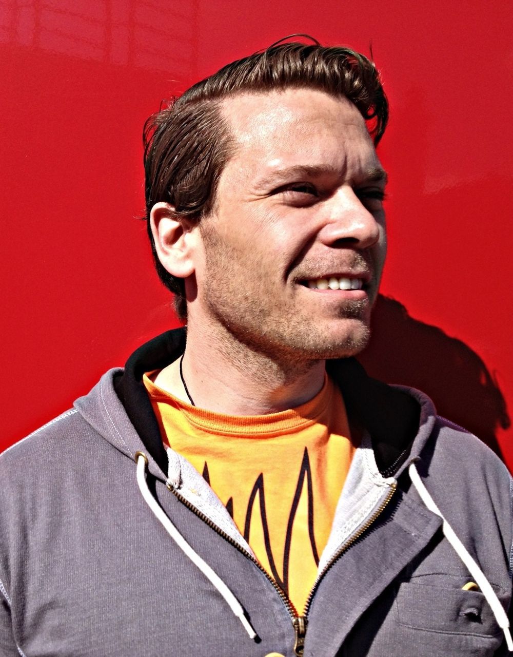 Smiling young man looking away against red wall