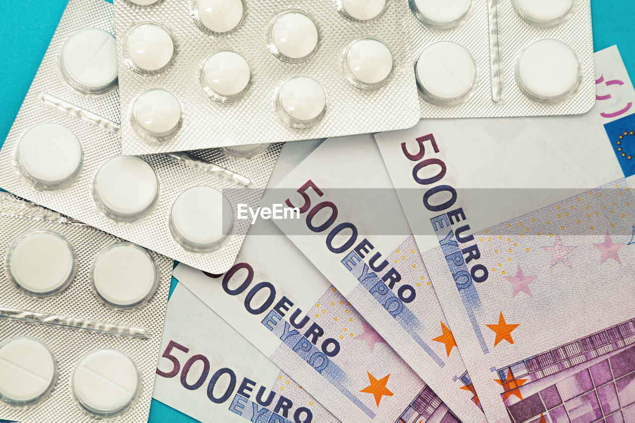 Money pills. medicine pills on euro bills on a blue background. covid-19 coronavirus pills are in