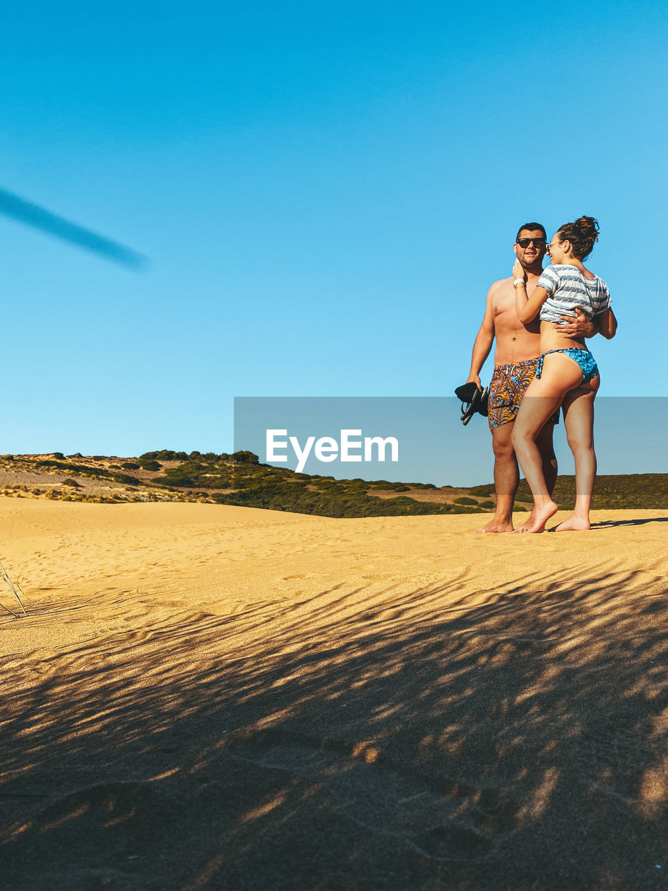 Woman with arms raised on beach against clear sky