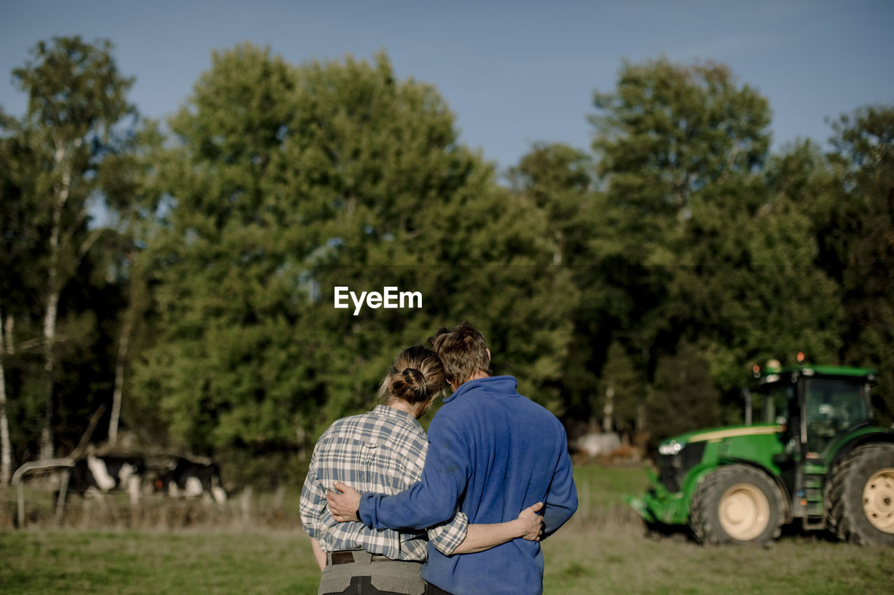Couple with arms around standing in farm on sunny day