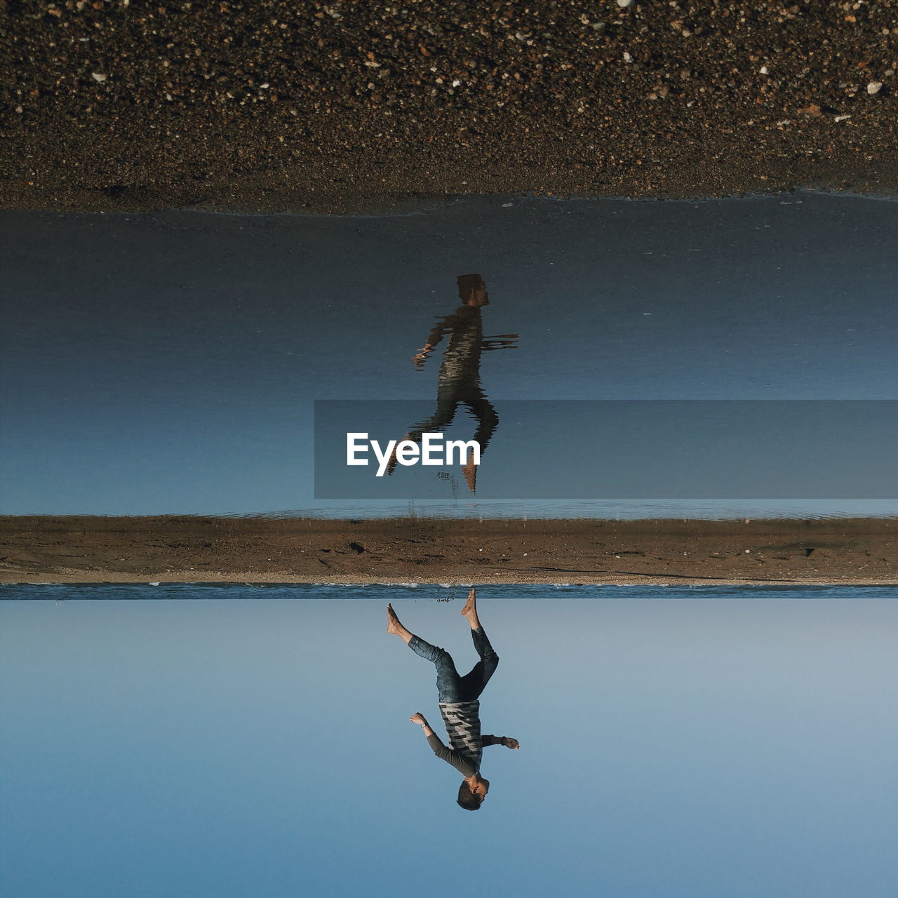 Reflection of man running at wet beach