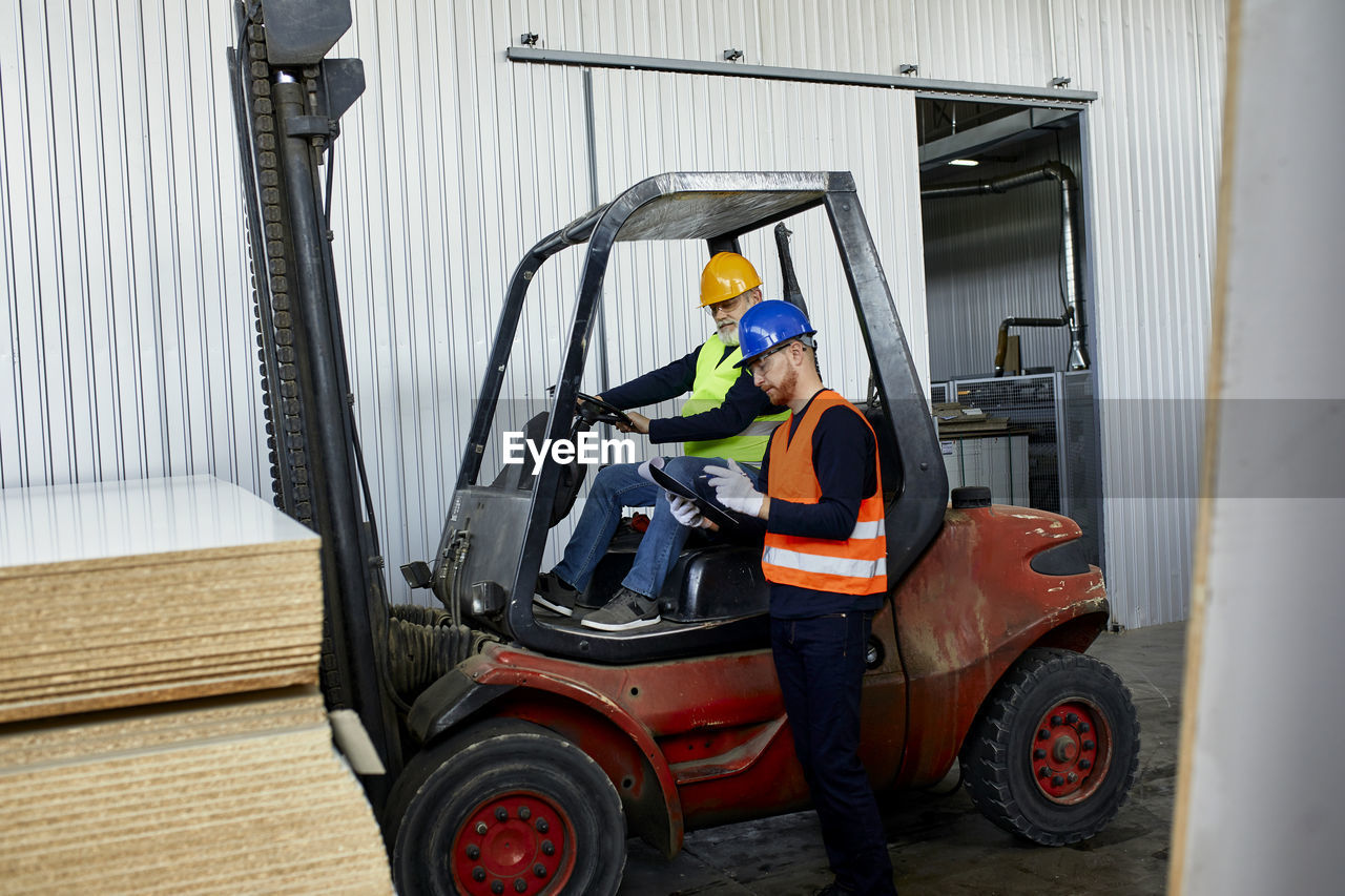 Man talking to worker on forklift in factory