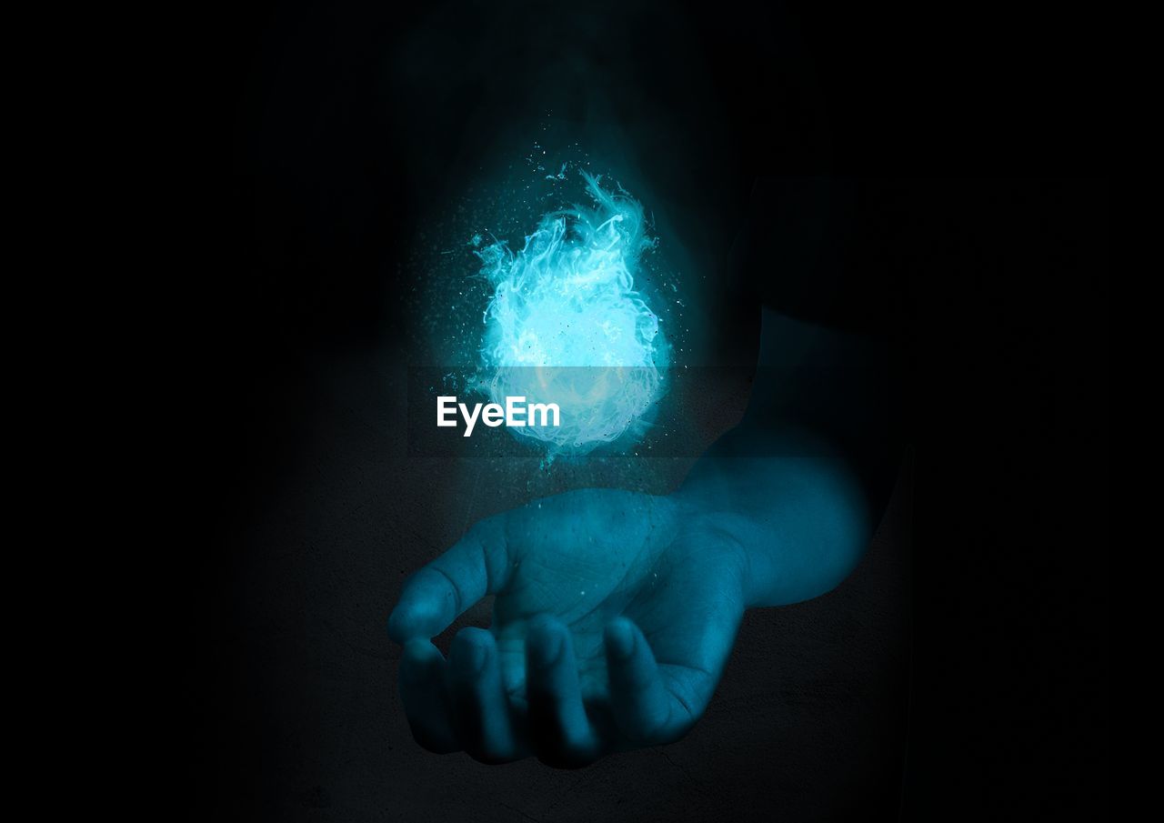 Digital composite image of hand holding illuminated light 