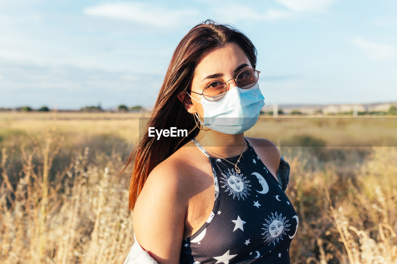 Serious teenager with a medical mask and sunglasses in the countryside