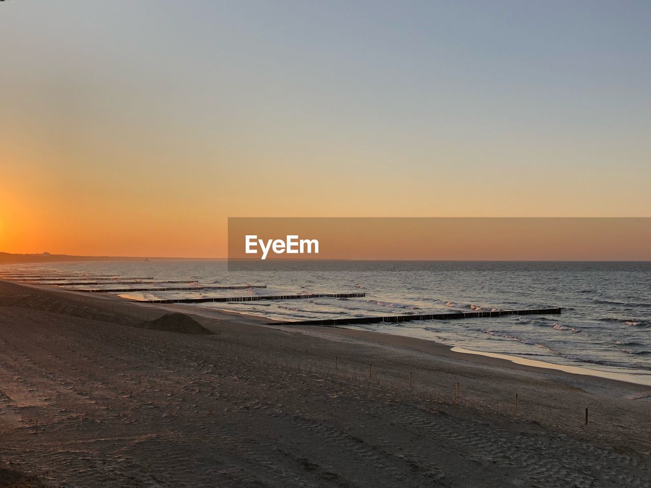 SCENIC VIEW OF BEACH AGAINST CLEAR SKY DURING SUNSET