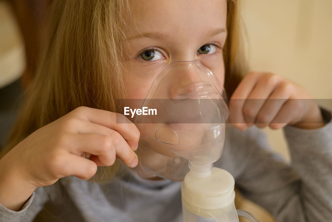 A sick child makes inhalation with a nebulizer at home, he holds a mask from which steam. the child