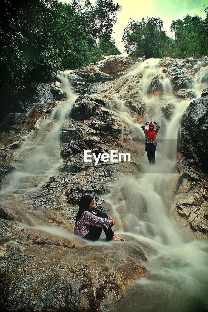 Women on rocks against waterfall