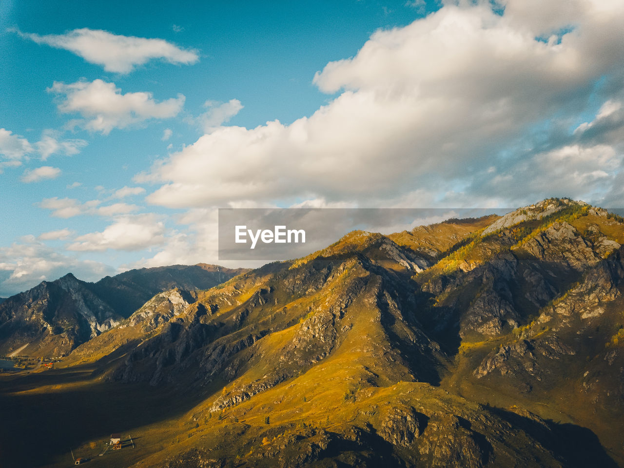 Bright yellow textured mountains against a blue sky, aerial view drone shot