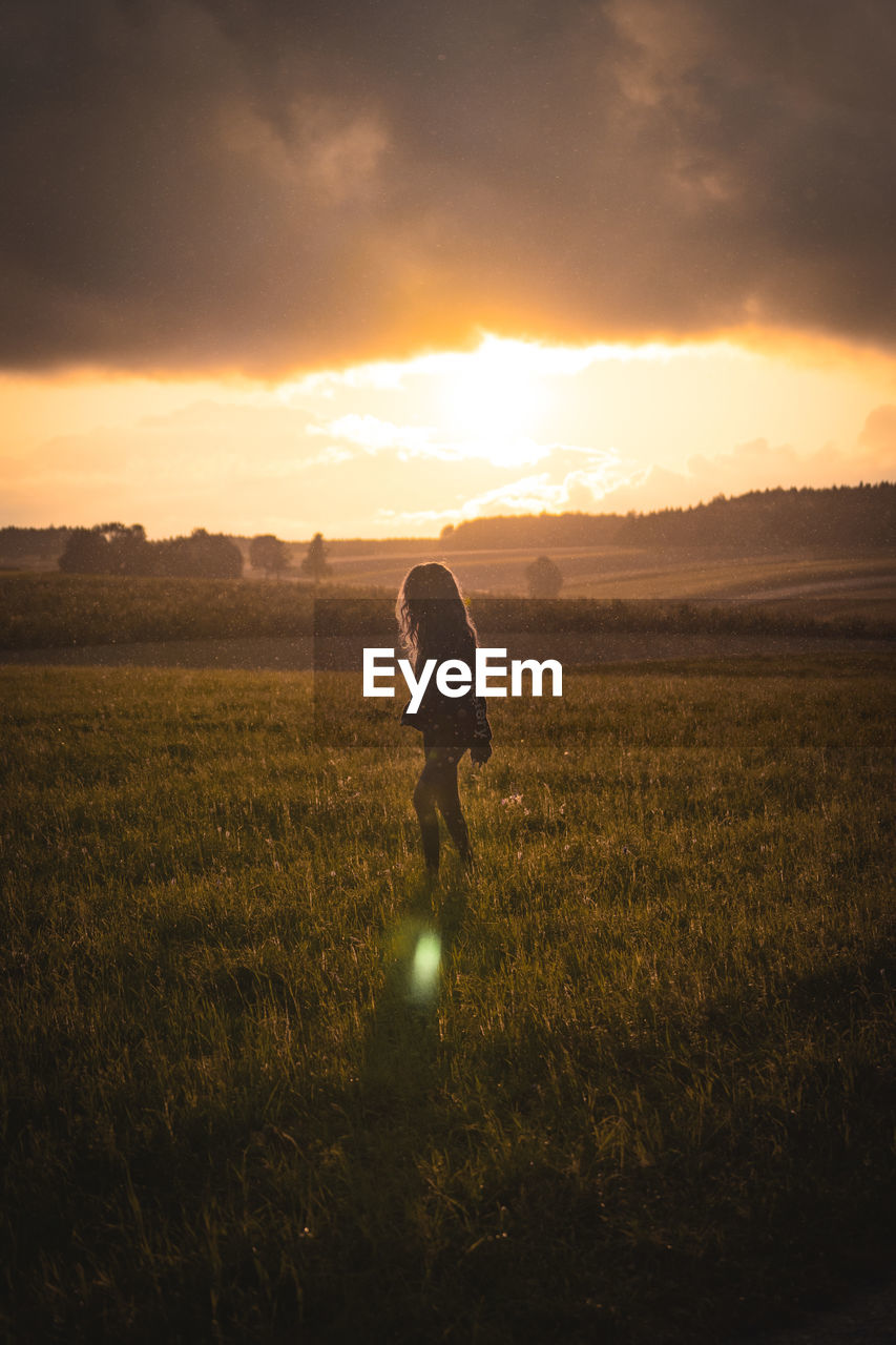 Woman on field against sky during sunset