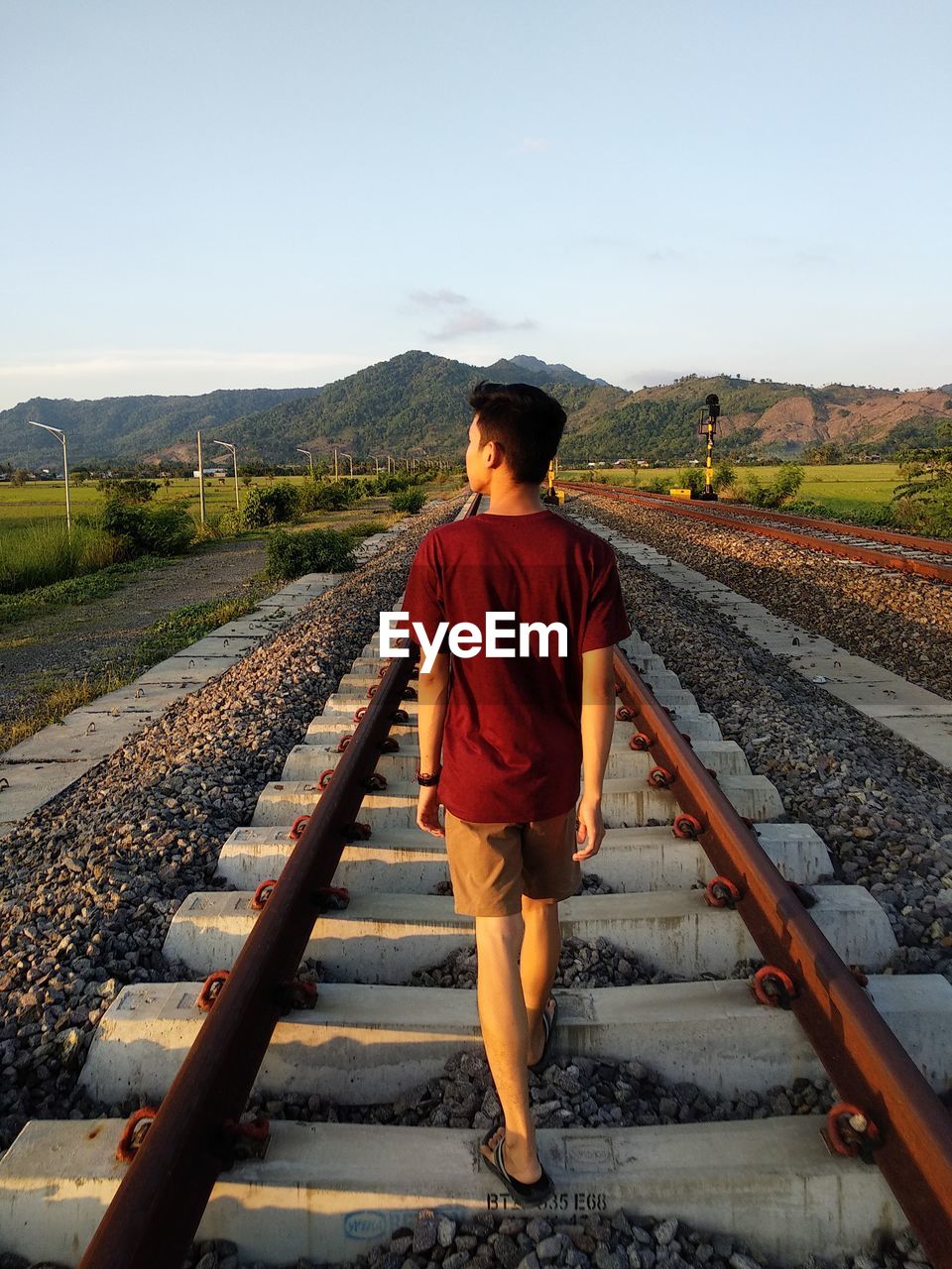 Rear view of man walking on railroad track