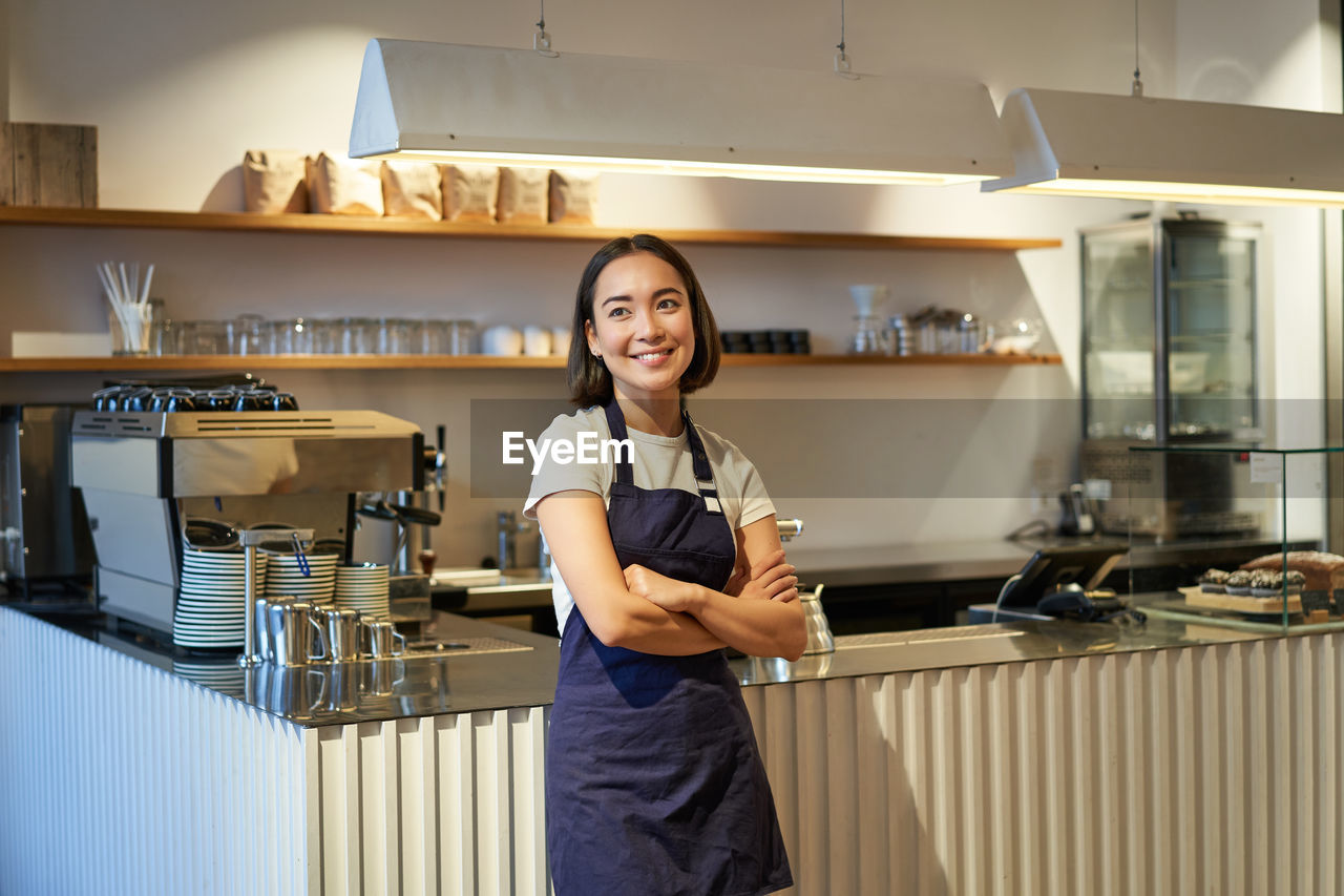 portrait of smiling young woman standing in kitchen