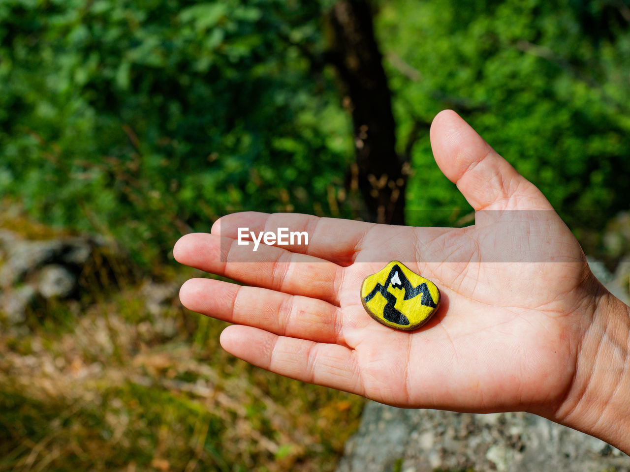 Hand palm hold chakra stone in heart shape with paint of mountains outline. magic spiritual esoteric