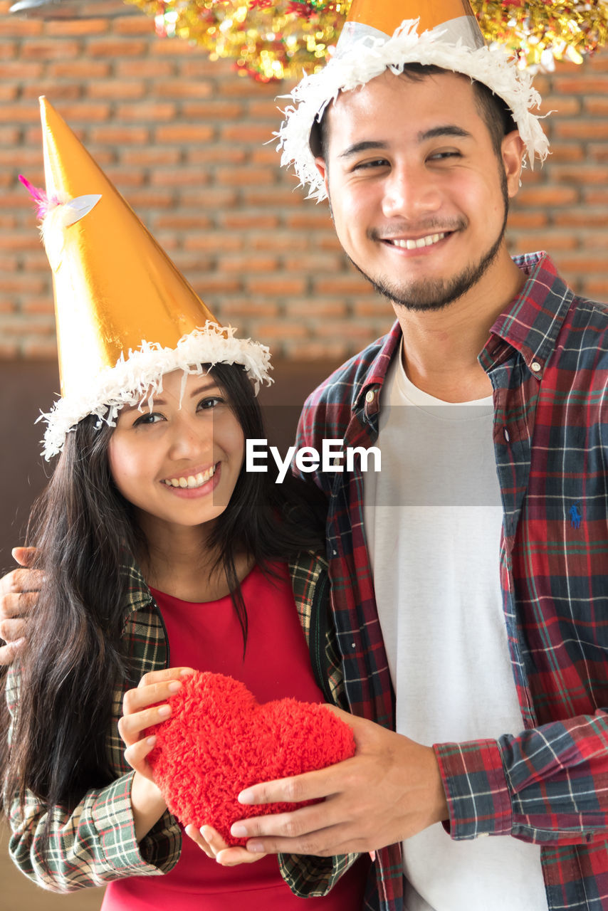 Man giving heart shape gift to girlfriend during christmas party