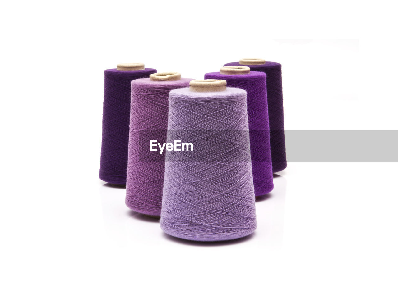 Close-up of purple thread spool over white background