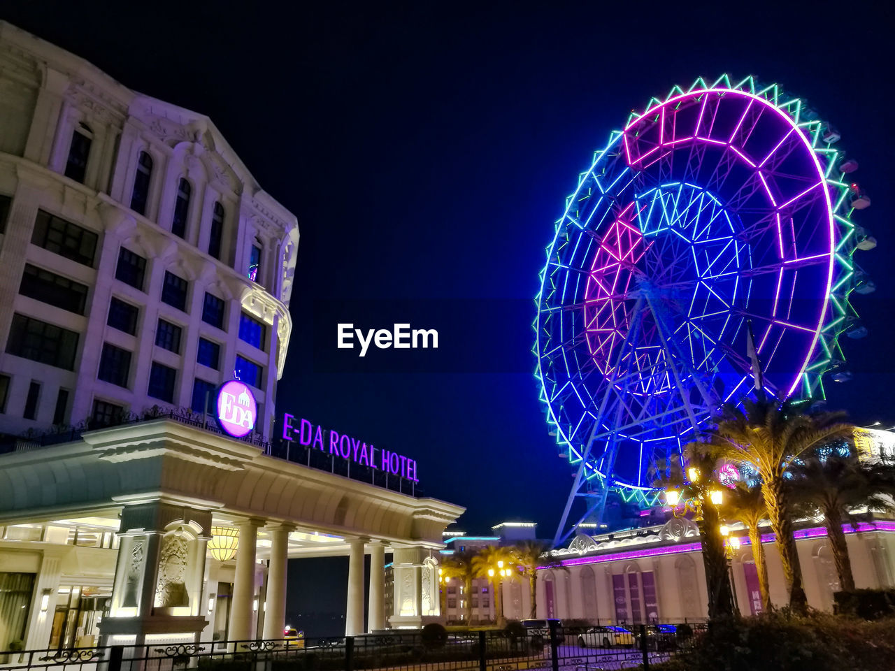 LOW ANGLE VIEW OF ILLUMINATED FERRIS WHEEL IN CITY AT NIGHT