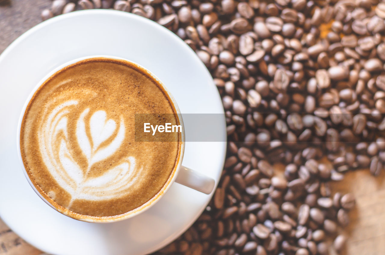 Close-up of frothy drink with roasted coffee beans on table