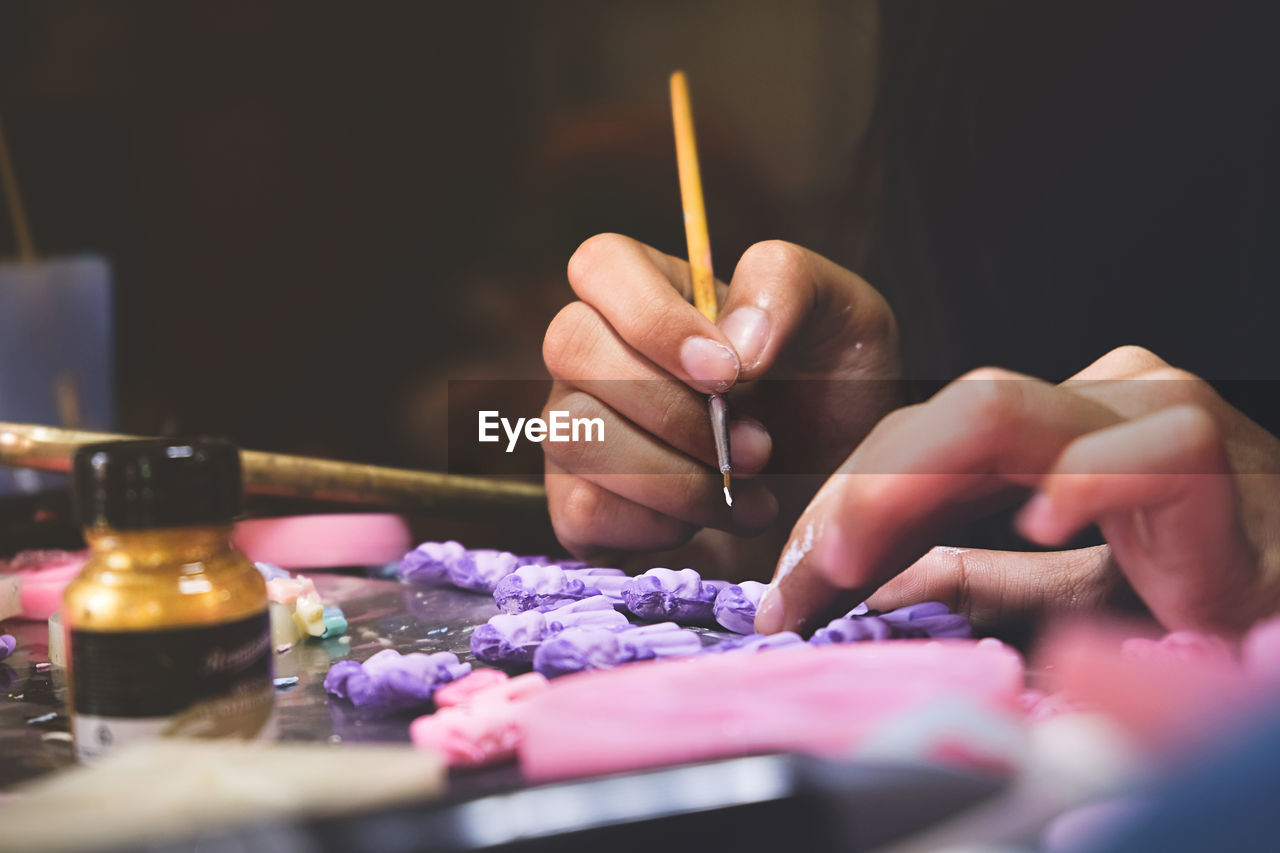 Cropped hands of person painting clay on table