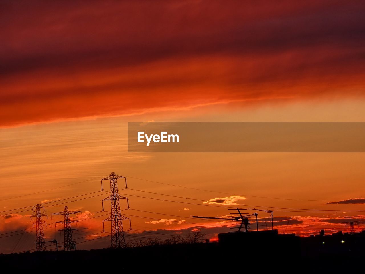 SILHOUETTE ELECTRICITY PYLON AGAINST DRAMATIC SKY AT SUNSET