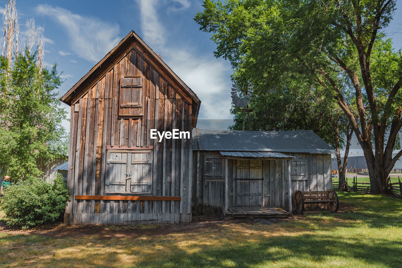 Tree shadows cast across an antique farm building on a summer day in madras, oregon, usa.