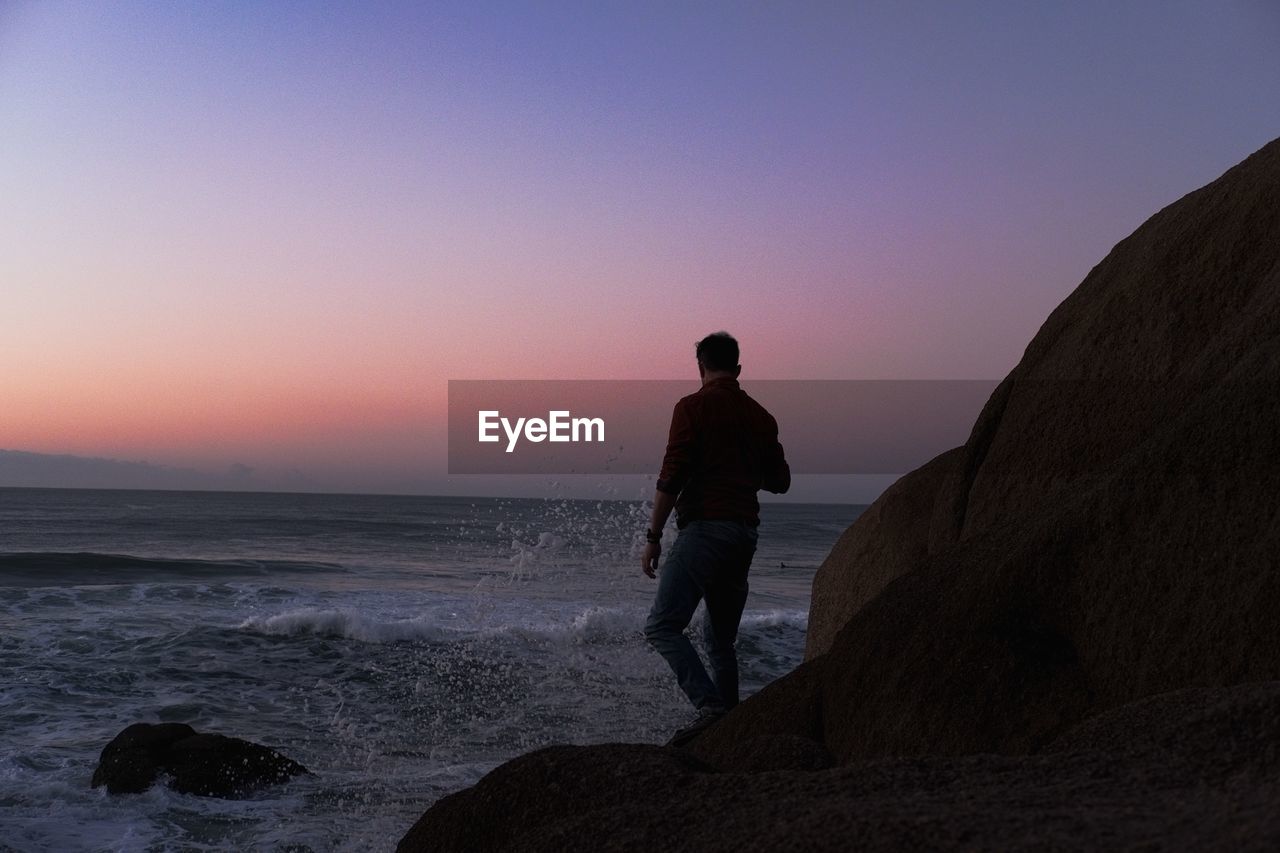 Man standing at the coast watching the sun rising