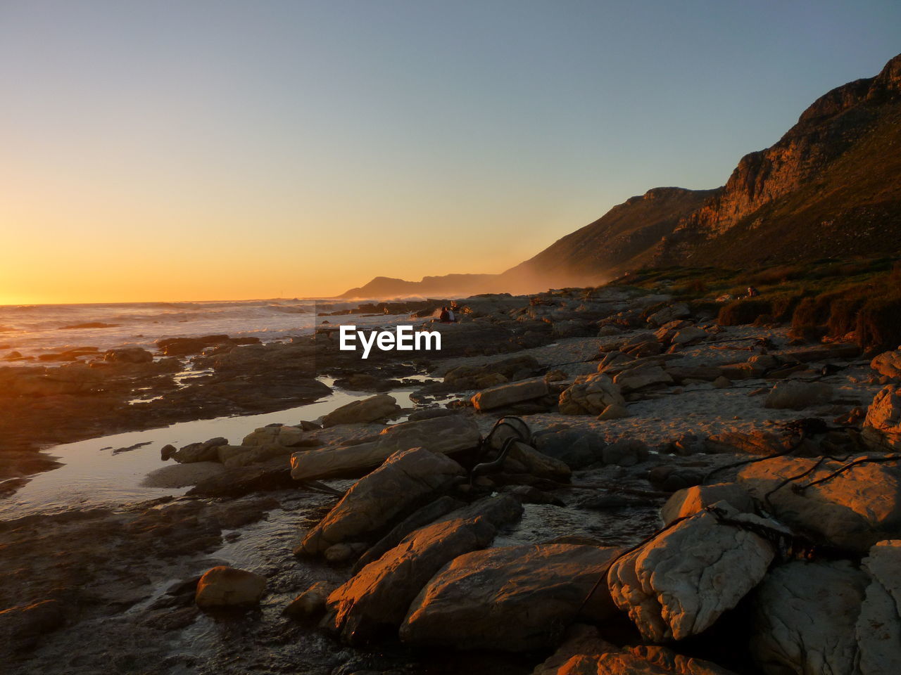 Scenic view of rocks against clear sky during sunset
