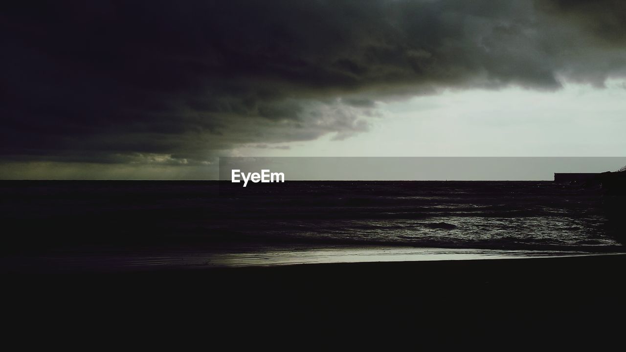 Scenic view of sea against storm clouds during sunset