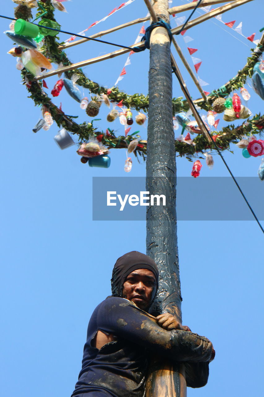 LOW ANGLE VIEW OF STATUE AGAINST TREE AND BLUE SKY