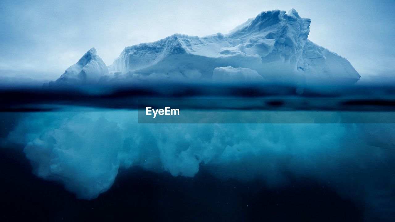 Iceberg floating on sea against sky