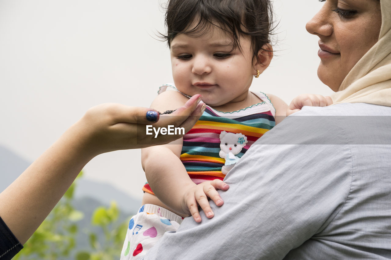 Cropped hand of woman showing food mother holding daughter outdoors