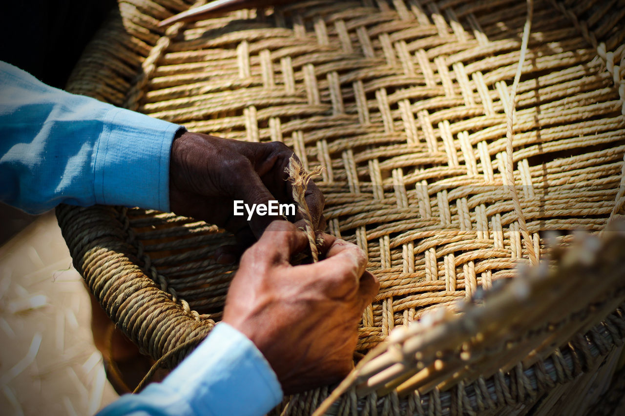 Skilled craftsman working manually a detailed bamboo wood armchair with his fingers and tools