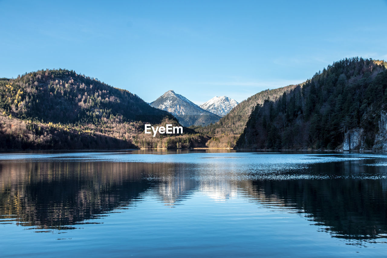 Scenic view of lake and mountains against blue sky