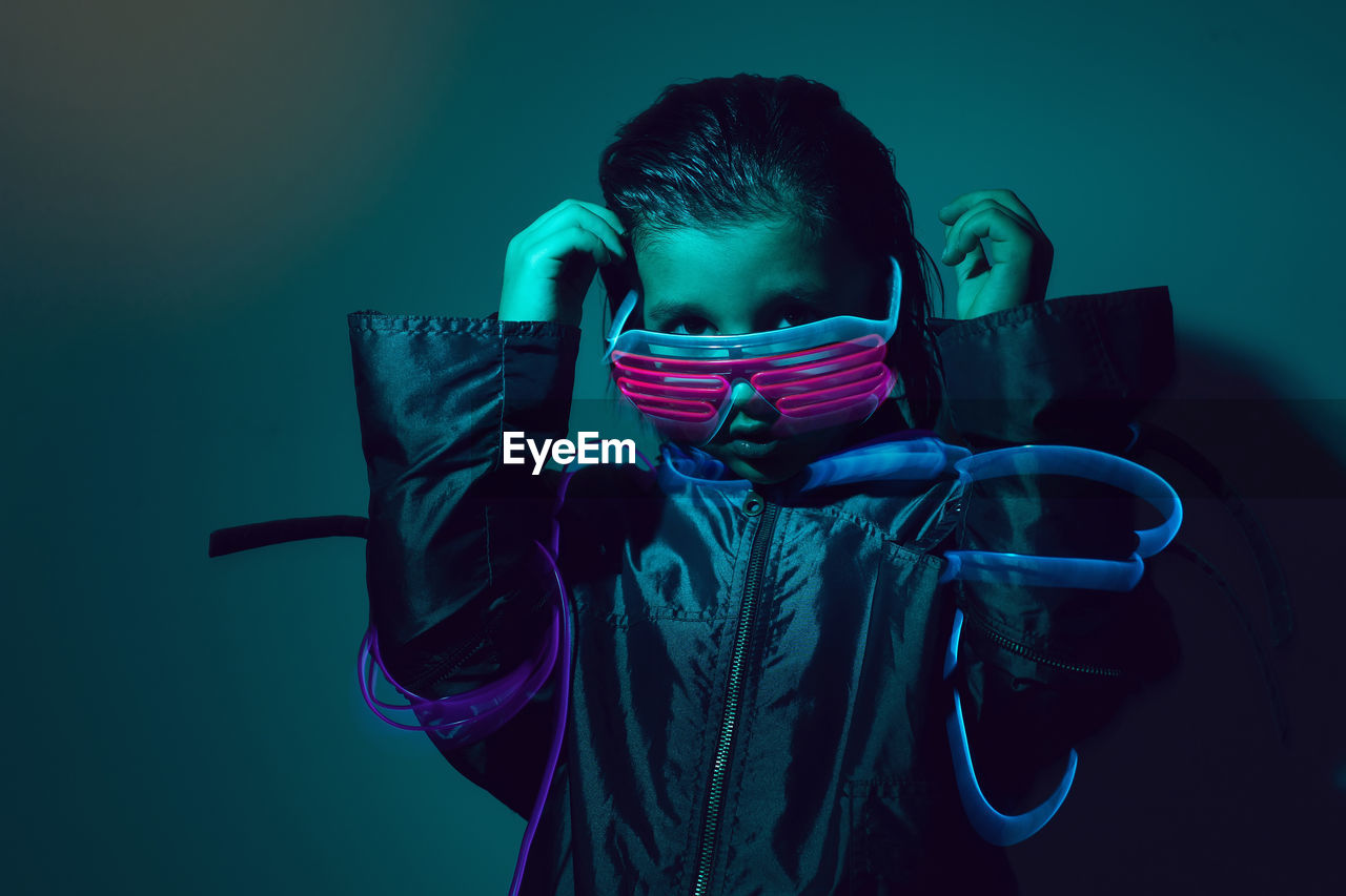 Portrait of a robot boy child from the future in neon glasses and jacket at night