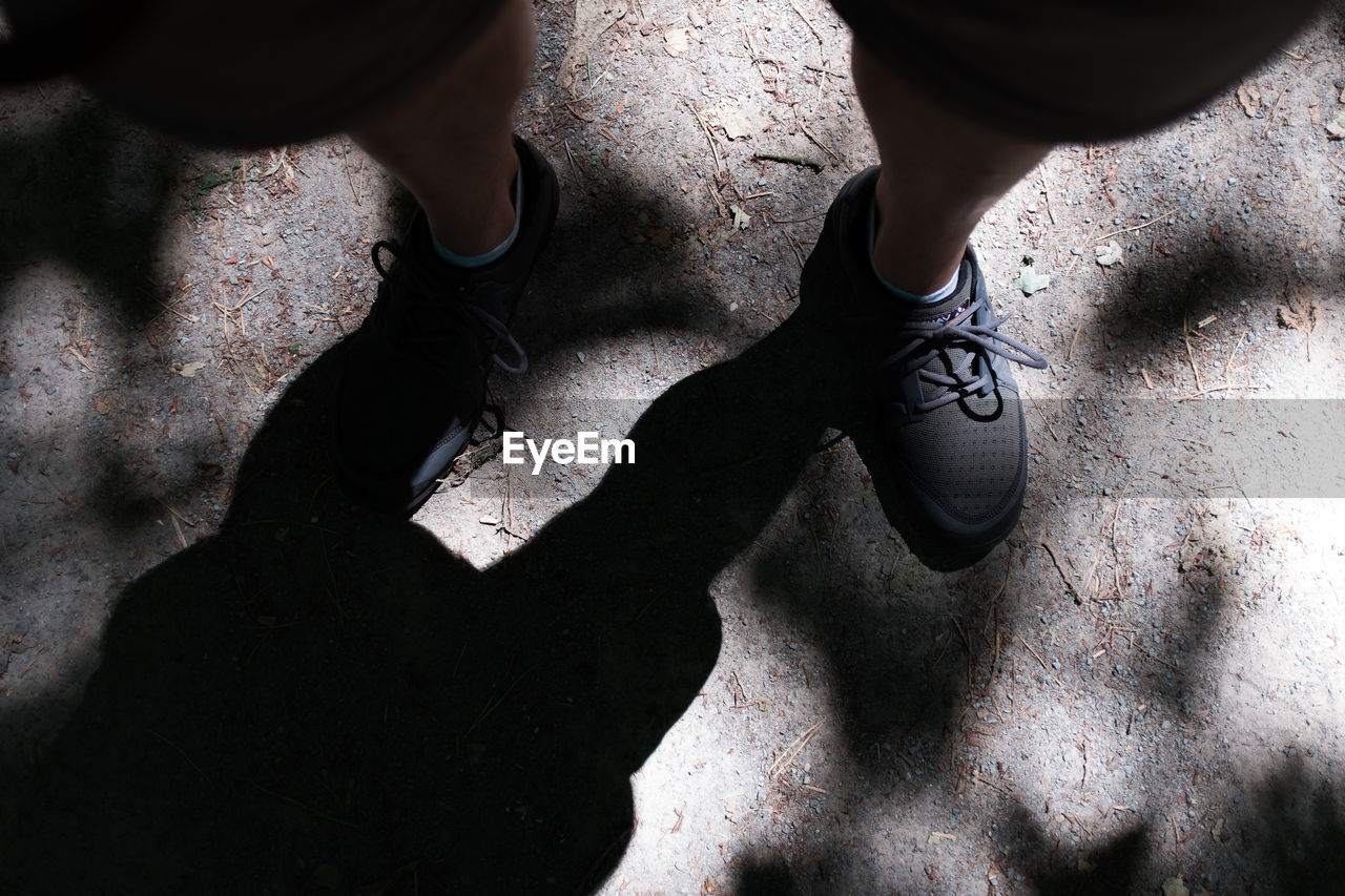 Low section of man wearing shoes while standing on field