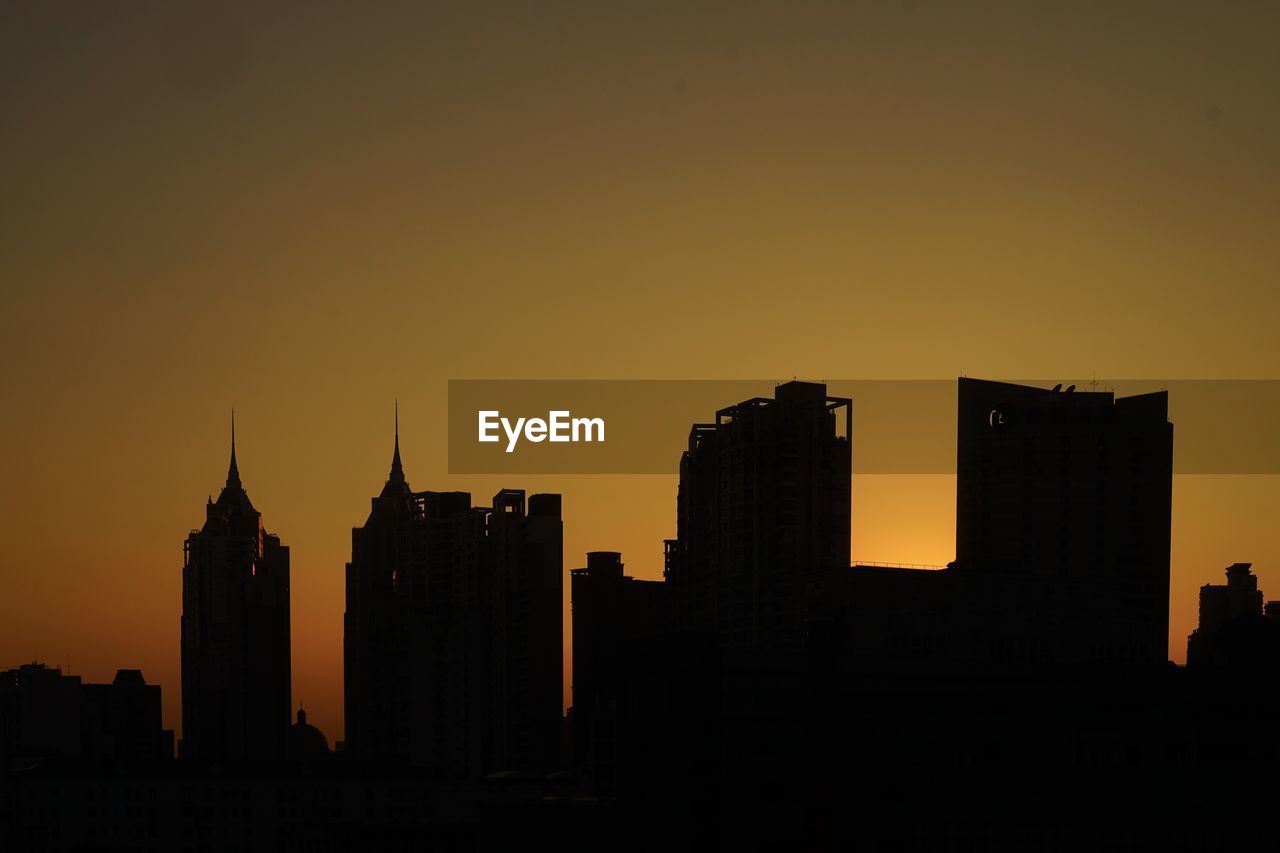Silhouette of buildings in city during sunset