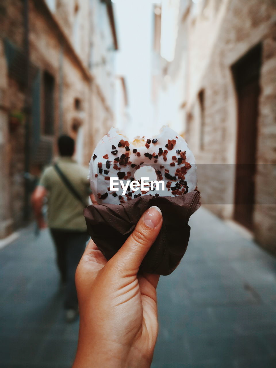 Cropped hand holding donut at street