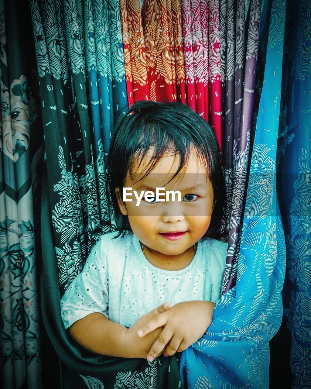 Portrait of girl standing by curtain